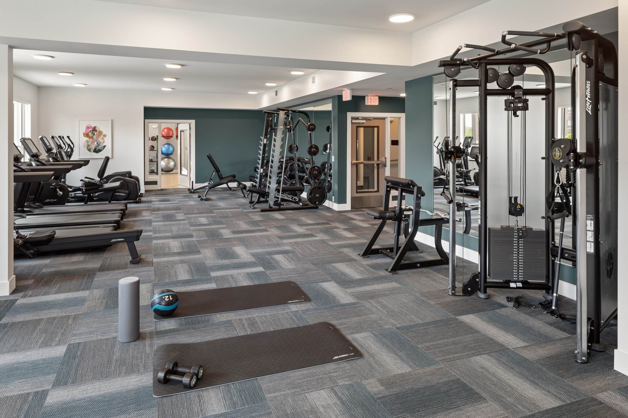 Aster at Riverdale Station fitness center with yoga mats, weight racks, and cardio equipment