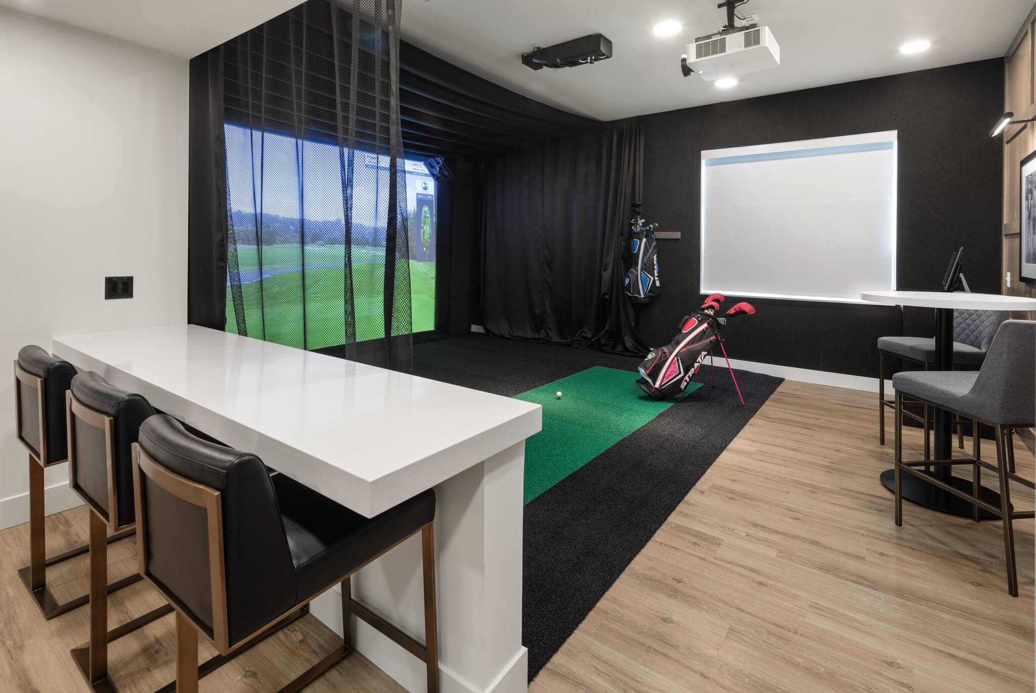Aster at Riverdale Station sports simulator room with golf clubs and countertop with seating