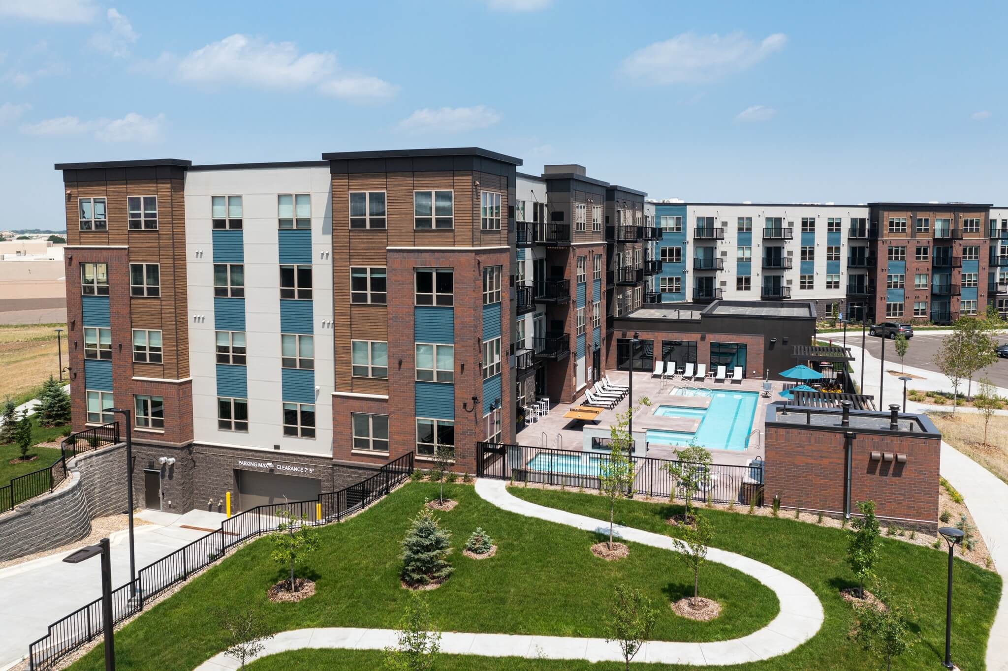 Aster apartments exterior showing building, green space, walking path, and pool