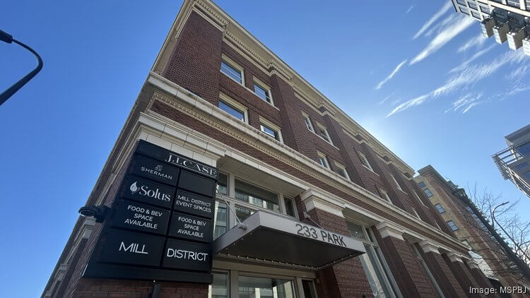 A low-angle view of a brick office building with business signs and a 229 College address canopy.